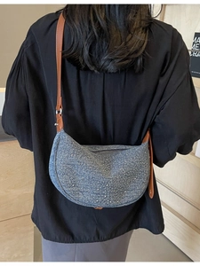 Blue denim crescent shoulder bag with silver studs and adjustable brown leather strap