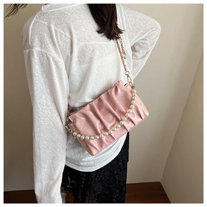 Détail du sac nuage plissé rose avec poignée en perles et chaîne porté par le modèle