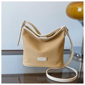 Detail of woven straw bucket bag showing leather trim and adjustable shoulder strap