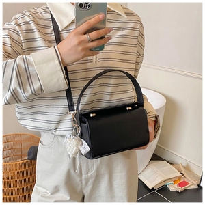 Close-up of black lychee grain leather square bag with elegant pearl heart pendant