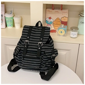 Detail of vintage striped canvas backpack showing flap closure and black leather buckle straps