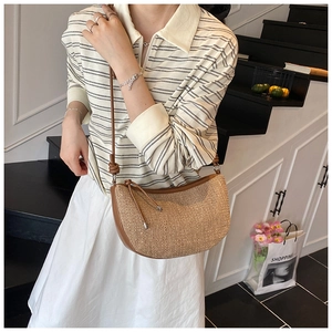 Detail of woven crescent hobo bag featuring brown leather trim and long shoulder strap
