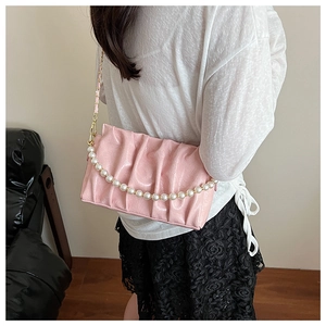 Pink pleated faux leather shoulder bag with pearl chain detail worn by model