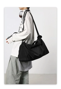 Détail du grand sac de voyage en nylon noir avec bandoulière réglable sur modèle