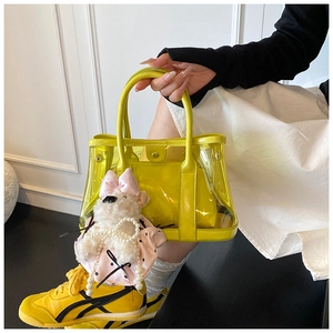 Détail du sac cabas en PVC jaune avec pochette en cuir et breloque chiot en peluche