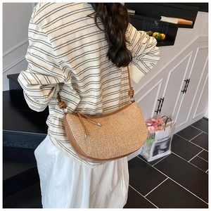 Detail view of woven shoulder bag featuring brown leather trim and knotted strap design