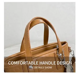 Detail of crocodile embossed leather handbag with sturdy handles and silver chain