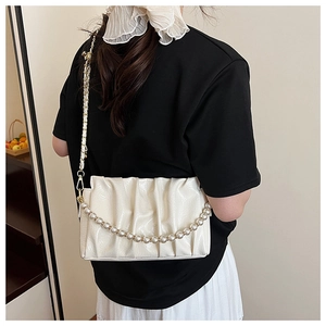 Detail of ruched beige shoulder bag featuring pearl chain and gold metal woven strap