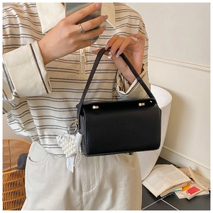 Close-up of black crossbody bag with lychee texture and pearl heart charm detail