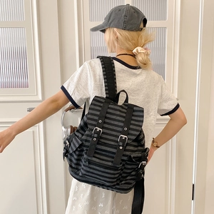 Close-up of retro striped canvas backpack featuring vintage flap design and buckle detail