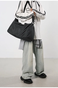 Détail du sac de fitness noir en nylon avec de larges bretelles et un tissu texturé