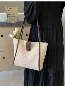 Minimalist beige woven tote bag with brown leather trim and shoulder strap in lifestyle setting