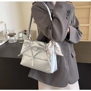 Détail du sac argenté métallisé avec nœuds et décoration d'écharpe en soie à cœur rose