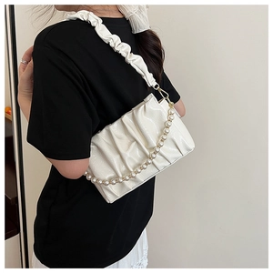 Close-up of white ruched cloud bag with glossy texture and large pearl chain detail