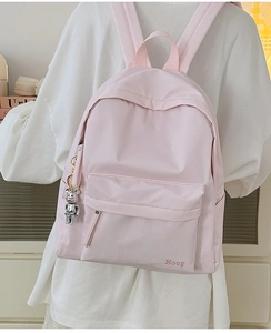 Detail of light pink casual backpack featuring embroidery and silver bear charm
