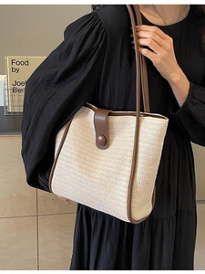 Minimalist woven straw tote bag with brown leather trim and shoulder straps in a side view