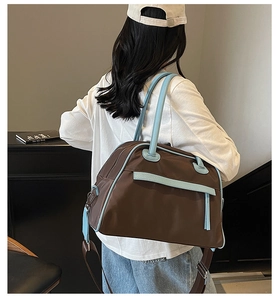 Detailed view of a large brown and light blue travel tote bag carried by a model