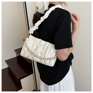 Detail of ruched cloud bag featuring elegant faux pearl chain and soft creamy texture