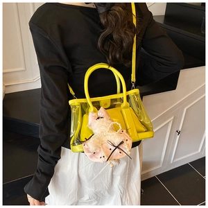 Détail du sac seau en PVC jaune avec charm chien en peluche porté à l'épaule