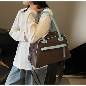 Dettaglio della grande borsa da viaggio bicolore con manici blu e pelle marrone