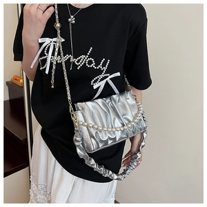 Détail du sac plissé argenté métallisé avec chaîne de perles et bandoulière large élégante