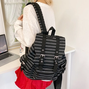 Detailed view of striped canvas backpack with retro flap cover and black strap buckles