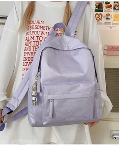 Detail of purple water-resistant nylon backpack with bear pendant and jacquard pattern