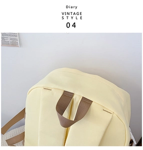 Gros plan du sac à dos vintage en toile jaune clair montrant les détails des poignées