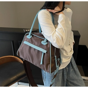 Detail of a large brown nylon tote with blue leather straps and decorative long tassels