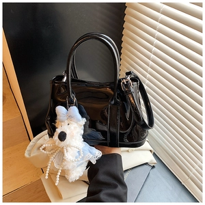 Gros plan du sac seau en cuir verni noir avec un joli petit ours en peluche blanc décoratif