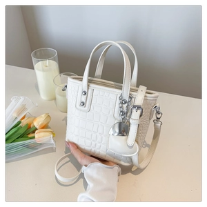 Detail of white crocodile embossed leather bucket bag with silver heart charm and metal rivets