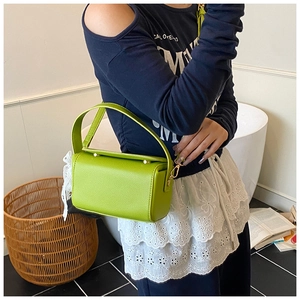 Detail of green pebble leather small handbag with top handles and golden metal hardware