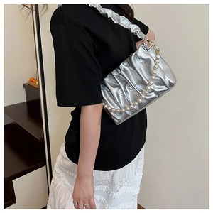 Detail of silver pleated cloud bag featuring large pearl chain and metallic texture strap