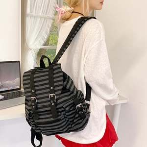 Detail of grey striped canvas backpack with flap cover and metallic buckles on model