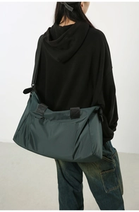 Détail du grand sac de voyage en nylon vert foncé porté par un mannequin en studio