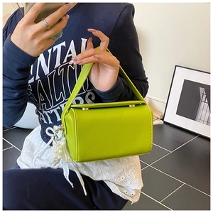 Close-up of bright green pebble leather mini bag with pearl charm and lace bow detail