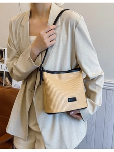 Minimalist hand-woven straw shoulder bag with dark brown leather straps and chic trim