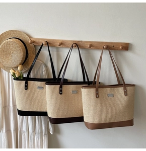 Detailed trio of woven straw tote bags with faux leather handles on wooden hooks