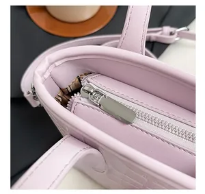 Close-up of silver metal zipper closure on light purple crocodile embossed bucket bag