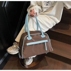 Dettaglio delle finiture in pelle blu sulla borsa da viaggio marrone con tracolla larga