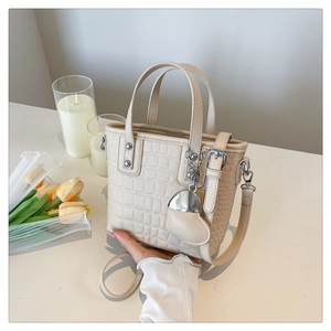 Detail of beige crocodile pattern handbag with heart charm and silver studs on side view