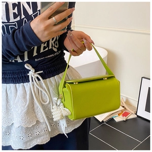 Detail of green litchi grain square bag with pearl lace bow charm held by a model