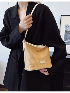Fashionable straw woven bucket bag with leather trim and shoulder strap in a minimalist setting