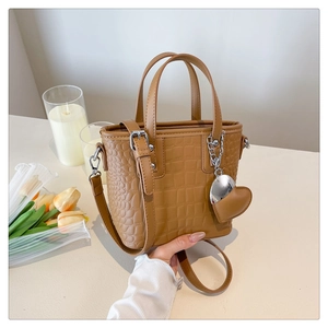 Brown crocodile texture bucket bag with silver chain and heart charm detail on a table