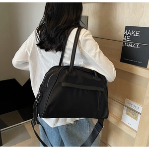 Grande borsa da viaggio in nylon nero indossata da una modella con un design moderno
