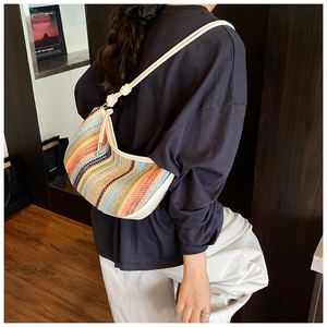 Detail shot of a woven dumpling bag with colorful wave patterns and a white knot strap