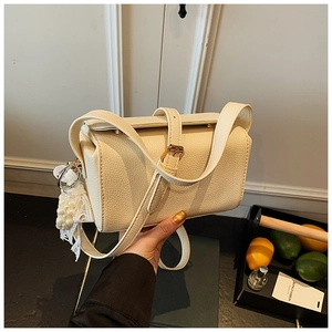 Detail of beige lychee pattern crossbody bag with pearl and lace floral charm accessory