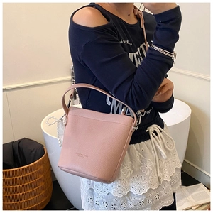 Dettaglio borsa a secchiello rosa in pelle martellata con ciondolo di perle