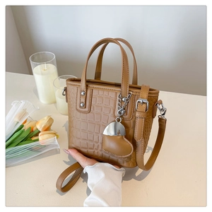 Detail of brown crocodile pattern crossbody bag with silver studs and heart charm