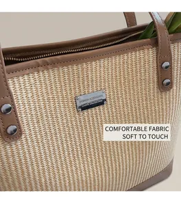 Close-up of woven straw tote bag featuring brown leather trim and silver rivet details
